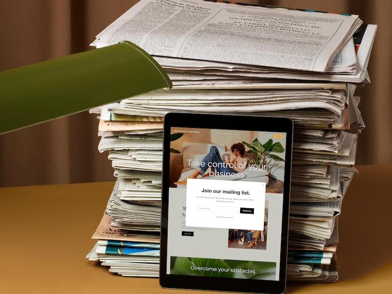A tablet leaning against a stack of newspapers