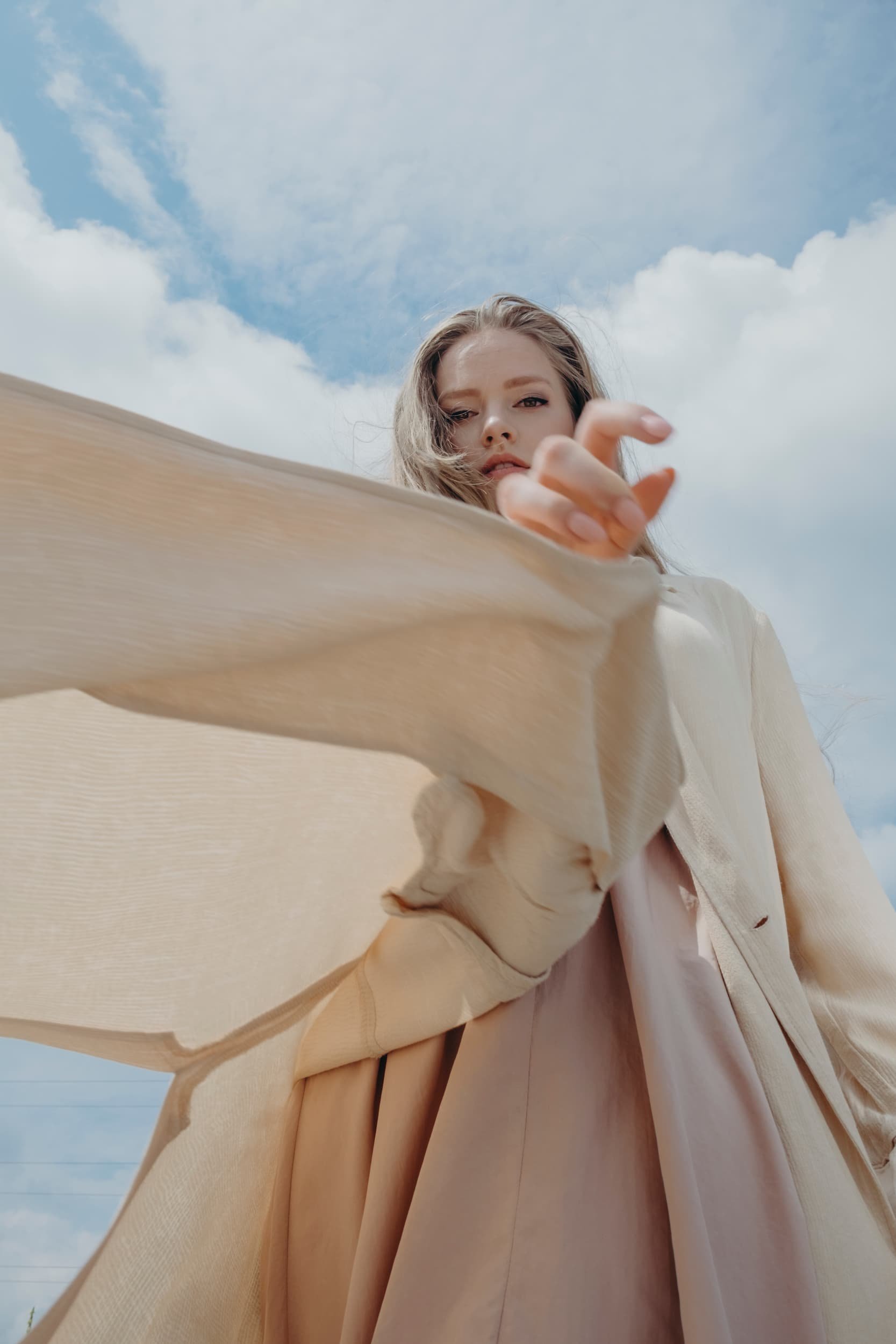 woman outside waving her beige linen jacket