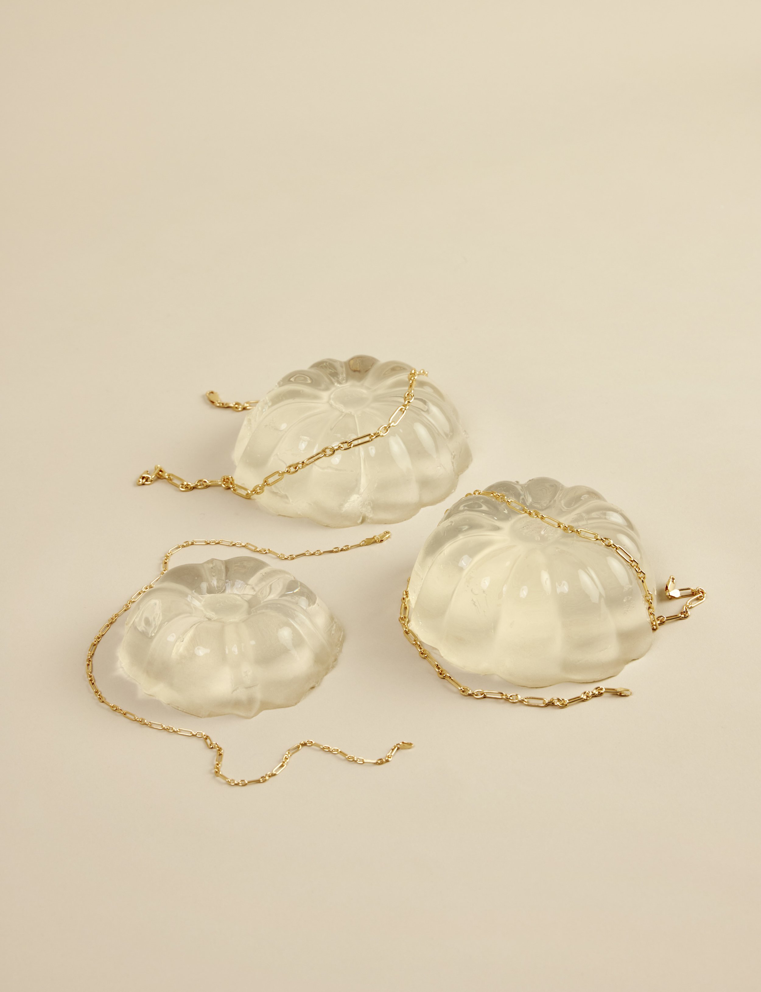 Woman wearing a white top with a delicate gold necklace and bracelet, looking to the side.