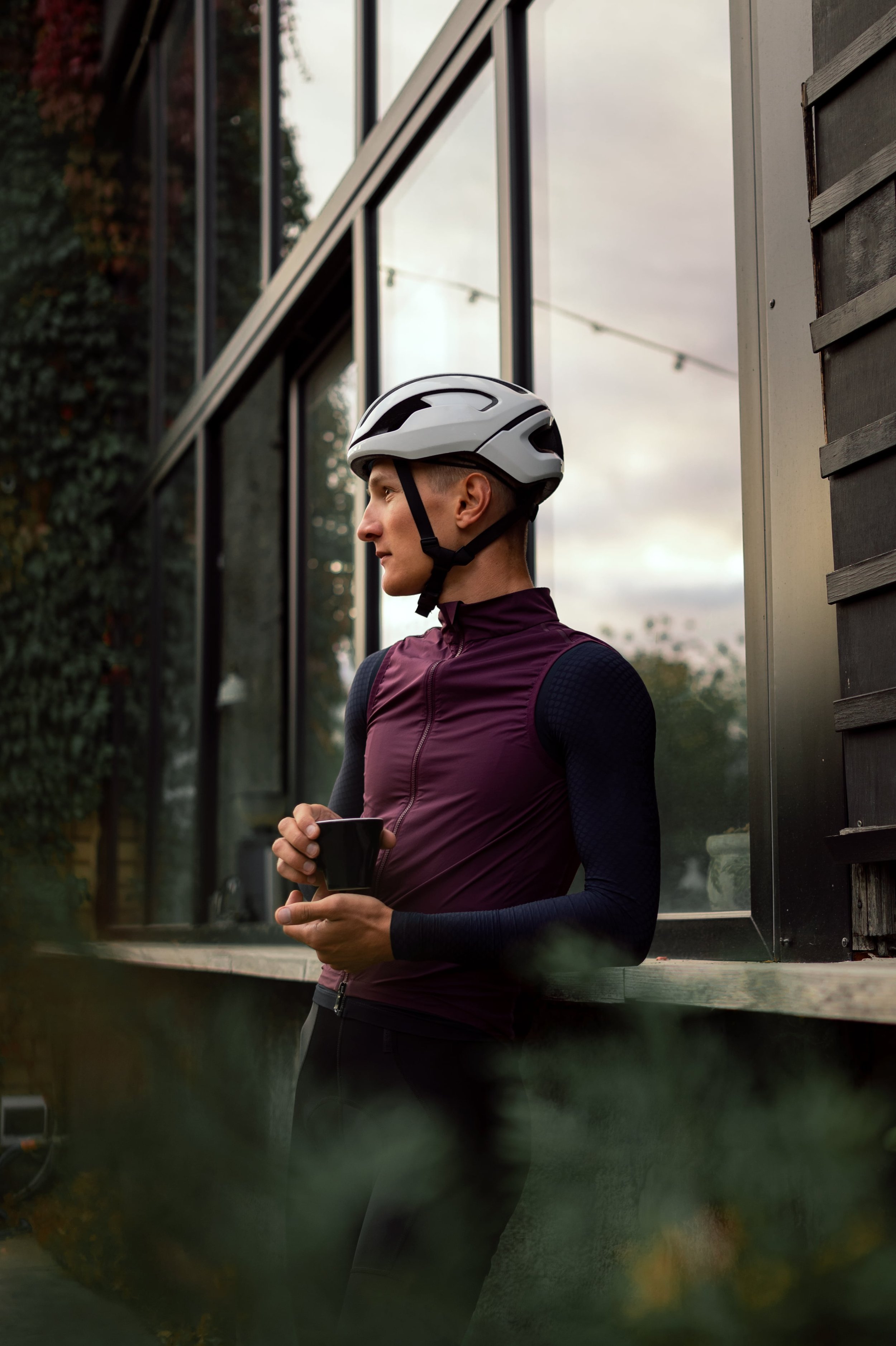 cyclist after training stands with a cup of coffee in an urban environment
